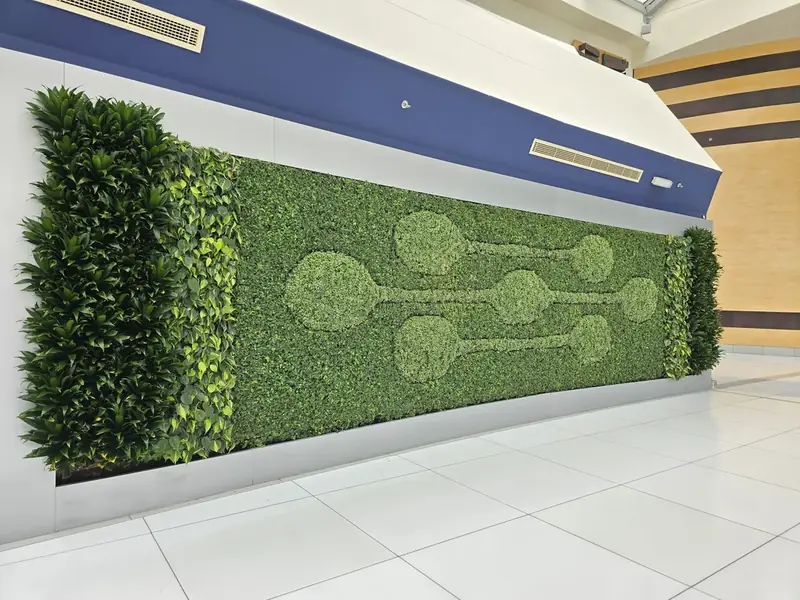 Long artificial green wall with a circular pattern cut into the foliage