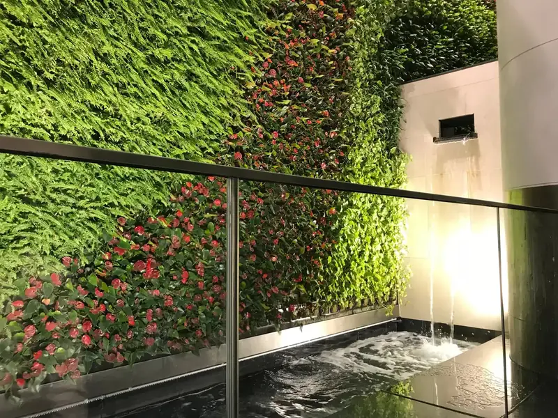 Living wall with flowering planting beside a lit water feature at Muscat International Airport